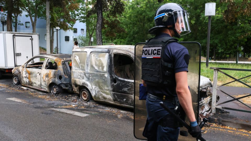 A French police officer stands guard next to vehicles burnt during a night of clashes between protesters and police, in Nanterre, Paris, on July 1, 2023.  - Yves Herman/Reuters