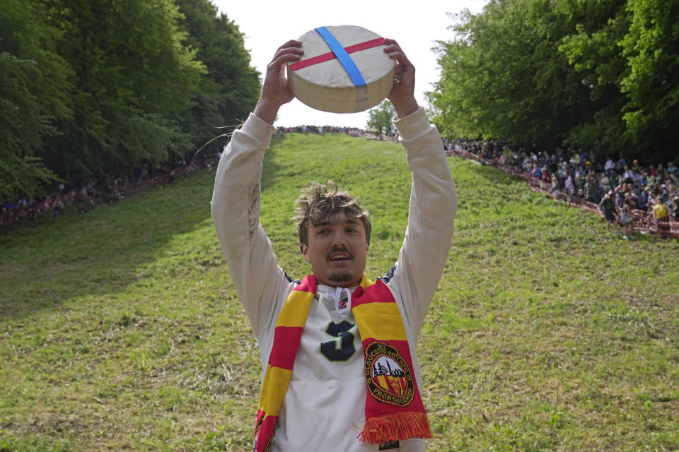 Cooper Cummings from the United States celebrates after winning a men's downhill during the Cheese Rolling contest at Cooper's Hill in Brockworth, Gloucestershire, Monday May 29, 2023. The Cooper's Hill Cheese-Rolling and Wake is an annual event where participants race down the 200-yard (180 m) long hill chasing a wheel of double gloucester cheese. (AP Photo/Kin Cheung)