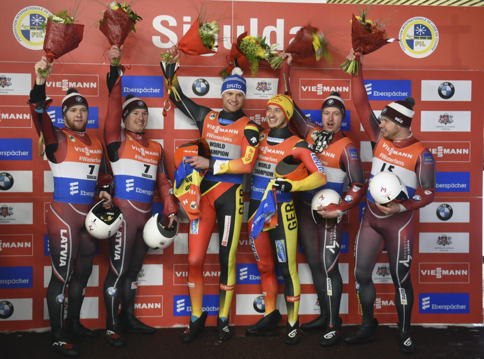 From left, Oskars Gudramovics and Peteris Kalnins of Latvia, second place, Toni Eggert and Sascha Benecken of Germany, first place, Andris Sics and Juris Sics of Latvia, third place, celebrate on the podium after their men's doubles race at the Luge World Cup event in Sigulda, Latvia, Saturday, Jan. 12, 2019. (AP Photo/Roman Koksarov)