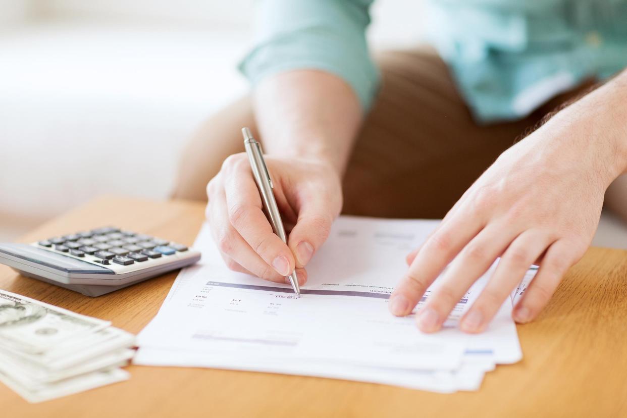 man's hands with calculator counting money and making notes at home