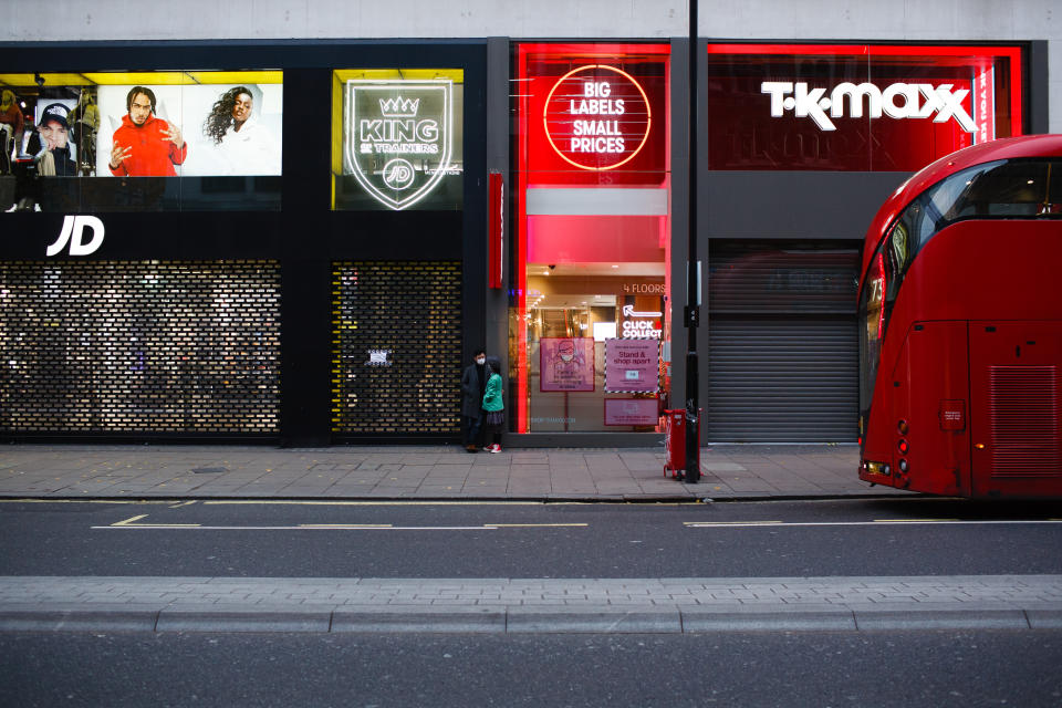 A couple wearing face masks stand between temporarily-closed shops on a quiet Oxford Street in London, England, on November 18, 2020. Across England non-essential shops as well as bars, restaurants and other hospitality businesses remain closed as part of the country's second national coronavirus lockdown, begun on November 5 and set to expire on December 2. British Prime Minister Boris Johnson, who has indicated that he does not wish for the lockdown to be extended, meanwhile remains in self-isolation at Downing Street after coming into contact with an MP last Thursday who later tested positive for covid-19. The prime minister himself, who was hospitalised with a serious case of the illness in the spring, has tested negative. (Photo by David Cliff/NurPhoto via Getty Images)