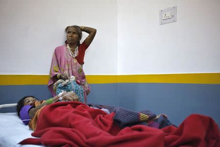 A woman, who underwent a sterilization surgery at a government mass sterilisation "camp", lies in a hospital bed for treatment as an attendant looks on at Chhattisgarh Institute of Medical Sciences (CIMS) hospital in Bilaspur, in the eastern Indian state of Chhattisgarh, November 13, 2014. REUTERS/Anindito Mukherjee
