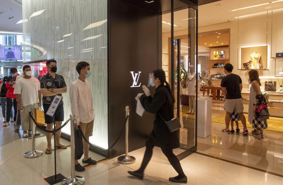 Patrons stand in a line to enter the Louis Vuitton shop at the upmarket shopping mall Siam Paragon in Bangkok, Thailand, Sunday, May 17, 2020. Thai authorities allowed department stores, shopping malls and other businesses to reopen from Sunday, selectively easing restrictions meant to combat the coronavirus. (AP Photo/ Gemunu Amarasinghe)