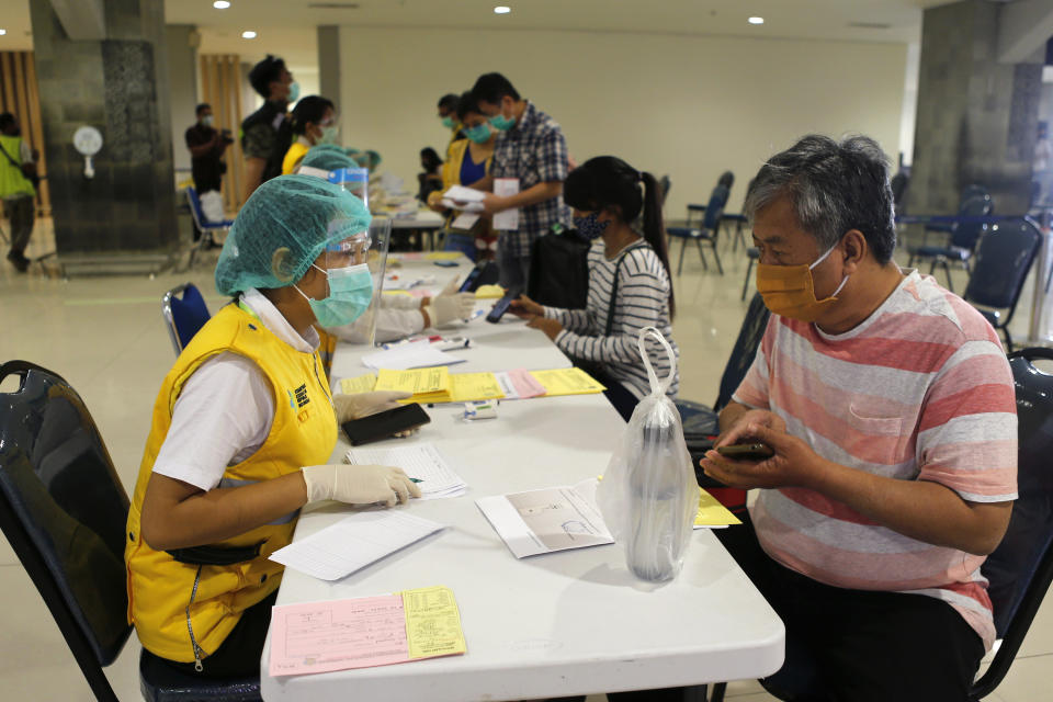 An officer checks passenger's health document on his arrival at Bali airport, Indonesia on Friday, July 31, 2020. Indonesia's resort island of Bali reopened for domestic tourists after months of lockdown due to a new coronavirus. (AP Photo/Firdia Lisnawati)