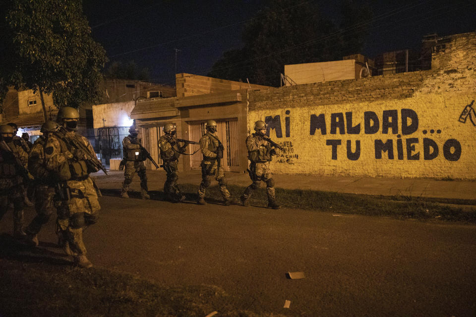 Members of the Special Operations Troops Company, (TOE) patrol La Tablada, a neighborhood with a high homicide rate in Rosario, Argentina, Thursday, April 29, 2021. The graffiti in the back reads in Spanish: "My evil, your fear." (AP Photo/Rodrigo Abd)