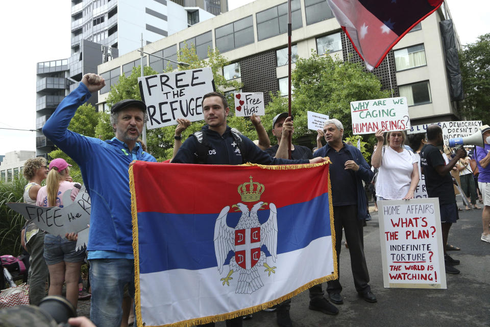 Protestors gather outside an immigration detention hotel where Serbia's Novak Djokovic is believed to stay, in Melbourne, Australia, Friday, Jan. 7, 2022. Locked in a dispute over his COVID-19 vaccination status, Djokovic was confined to the immigration detention hotel in Australia on Thursday as the No. 1 men's tennis player in the world awaited a court ruling on whether he can compete in the Australian Open later this month. (AP Photo/Hamish Blair)