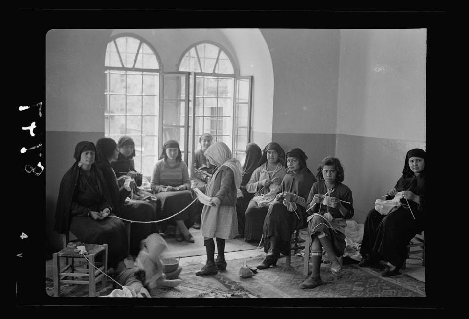 A black and white photo of women knitting.