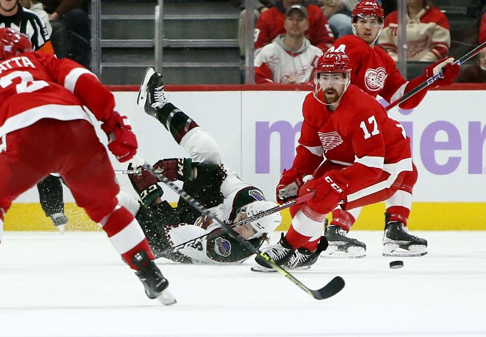 Arizona Coyotes defenseman Jakob Chychrun, center, hits the ice while trying to pass the puck against Detroit Red Wings defenseman Filip Hronek (17) and center Pius Suter, rear, during the second period of an NHL hockey game Friday, Nov. 25, 2022, in Detroit. (AP Photo/Duane Burleson)