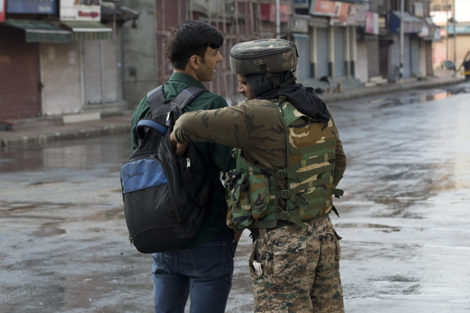 An Indian Paramilitary soldier checks the bag of a Kashmiri man during curfew in Srinagar, Indian controlled Kashmir, Thursday, Aug. 8, 2019. The lives of millions in India's only Muslim-majority region have been upended since the latest, and most serious, crackdown followed a decision by New Delhi to revoke the special status of Jammu and Kashmir and downgrade the Himalayan region from statehood to a territory. Kashmir is claimed in full by both India and Pakistan, and rebels have been fighting Indian rule in the portion it administers for decades. (AP Photo/Dar Yasin)