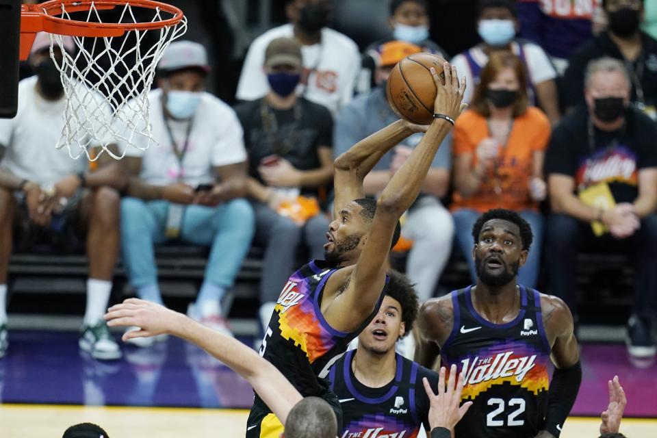 Phoenix Suns forward Mikal Bridges, top left, grabs a rebound against the Los Angeles Clippers as Suns forward Cameron Johnson, center, and center Deandre Ayton, right, look on during the second half of Game 1 of the NBA basketball Western Conference finals Sunday, June 20, 2021, in Phoenix. (AP Photo/Ross D. Franklin)