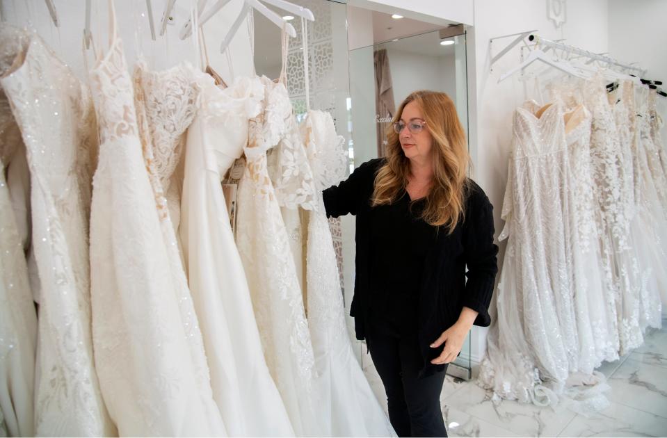 Sheryl Giles, owner of Sheryl Giles Bridal Couture, adjust dresses on a rack at her store in Lincoln Center in Stockton on Apr. 23, 2024.