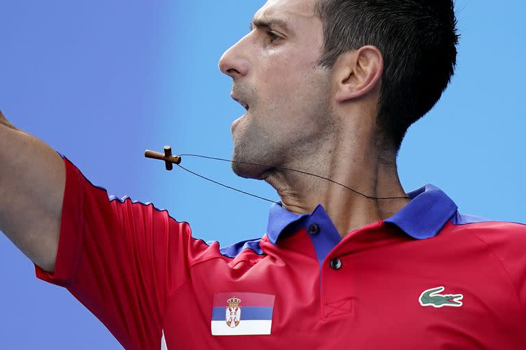 Un collar cuelga del cuello de Novak Djokovic cuando regresa a Hugo Dellien, de Bolivia, durante la competencia de tenis en los Juegos Olímpicos de Verano de 2020, el sábado 24 de julio de 2021 en Tokio, Japón.
