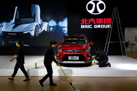 FILE PHOTO: People clean at the booth of the automaker BAIC Group where its Beijing Electric Vehicle Co Ltd's (BJEV) electric SUV EX360 is displayed, at the IEEV New Energy Vehicles Exhibition in Beijing, China October 18, 2018. REUTERS/Thomas Peter/File Photo