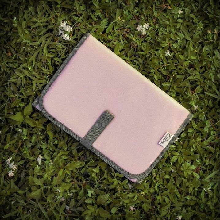 Pink laptop sleeve on grass, minimalistic design, suitable for outdoor use