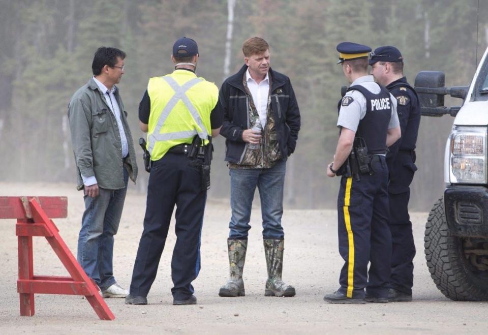 Alberta Wildrose Leader Brian Jean, centre, talkswith police near a wildfire in Fort McMurray, Alta., on Thursday, May 5, 2016. Jean’s house was burned down in the fire. An ever-changing, volatile situation is fraying the nerves of residents and officials alike as a massive wildfire continues to bear down on the Fort McMurray area of northern Alberta. THE CANADIAN PRESS/Jason Franson