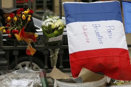 A French flag with the message 'Paris Brussels Solidarity' is displayed next to flowers with the colors of the Belgium flag in front of the Belgium embassy in Paris, France, March 23, 2016 in tribute to the victims of bomb attacks in Brussels. REUTERS/Gonzalo Fuentes