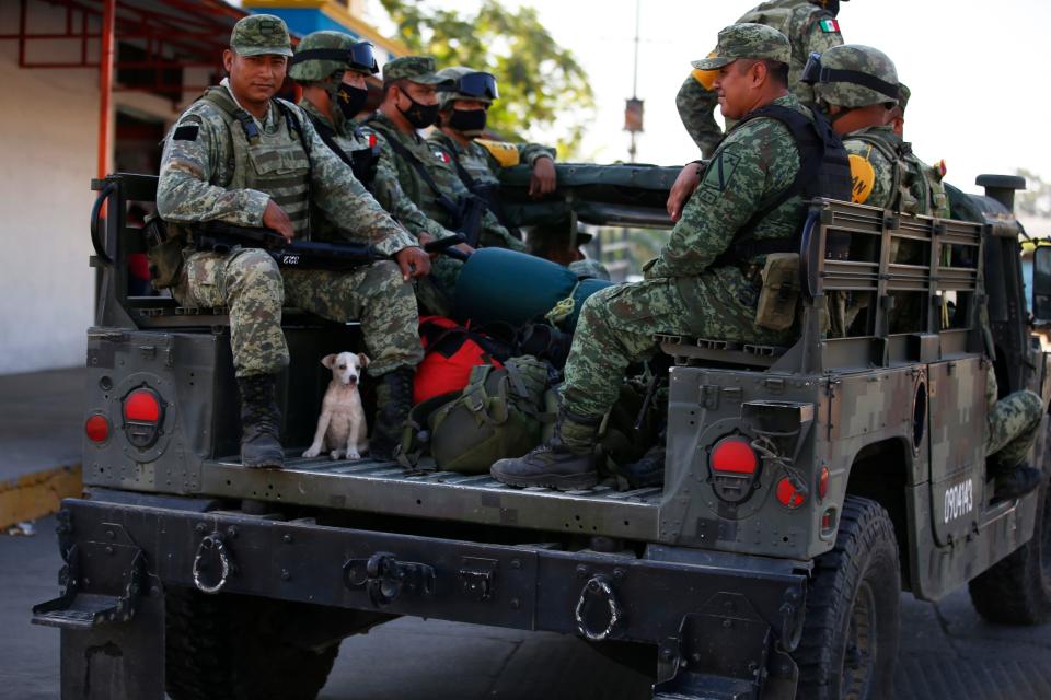 Mexican soldier Gaspar Sanchez sits over his recently adopted puppy 'Cloee' following his troop's overnight patrol along the Suchiate River, the natural border with Guatemala near Ciudad Hidalgo, Mexico, Jan. 21, 2021, after a caravan of Honduran migrants dissipated before reaching the river. Sanchez said he adopted the puppy from a litter of street dogs near his base in Tapachula.