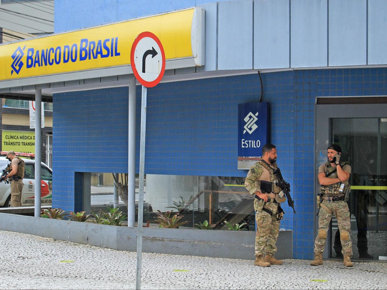 Police officers stand guard outside the bank which robbers attacked just after midnight, in the city of Criciuma (AFP via Getty Images)