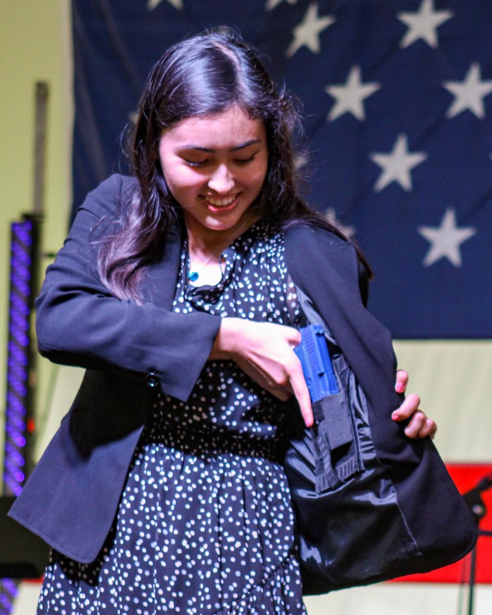 A participant in the Concealed Carry Fashion show reveals a gun hidden beneath her blazer.