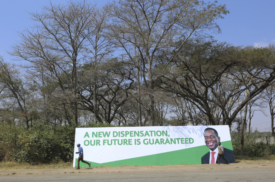 A man walks past a banner ahead of Sunday's inauguration of Zimbabwean President Emmerson Mnangagwa in Harare, Saturday, Aug, 25, 2018. Opposition leader Nelson Chamisa said he respectfully rejects the court ruling upholding Mnangagwas narrow election win.(AP Photo/Tsvangirayi Mukwazhi)