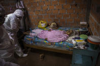 Government team members prepare to remove the body of Cruz Amanda Vargas, who died from symptoms related to the new coronavirus at the age of 84, from inside her home, in the Shipibo Indigenous community of Pucallpa, in Peru’s Ucayali region, Monday, Aug. 31, 2020. At the peak of the outbreak in May and June, around 15 people were dying a day, said Juan Carlos Salas, director of Ucayali’s regional health agency. (AP Photo/Rodrigo Abd)