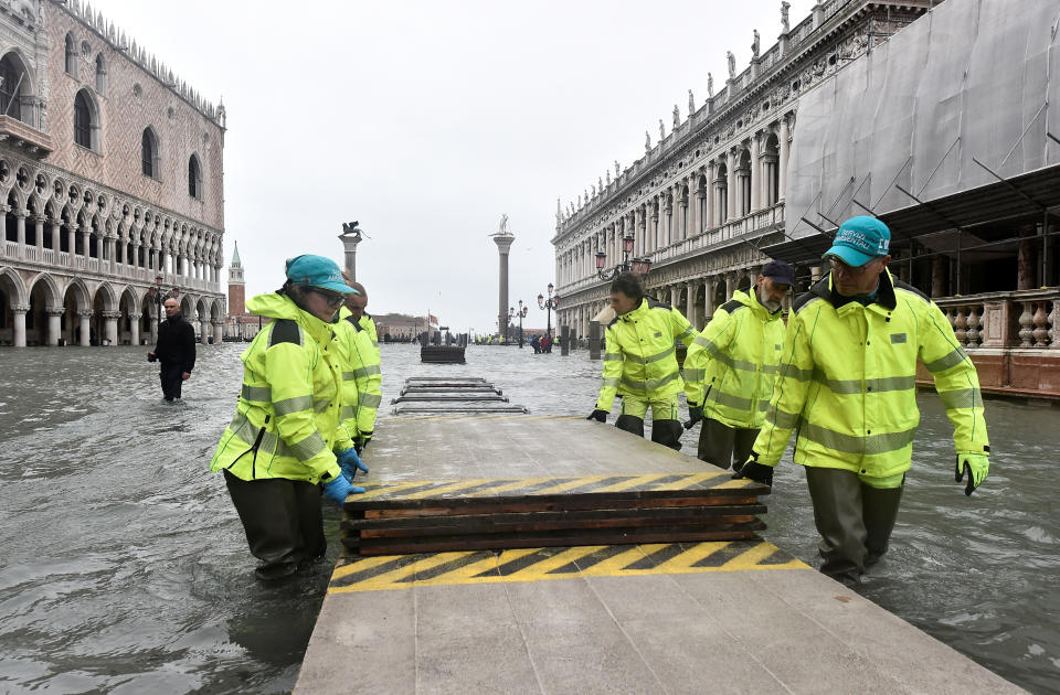 Workers dismantle a makeshift walkway over the flooded St. Mark's Square, as high tide reaches peak, in Venice, Italy November 15, 2019. REUTERS/Flavio Lo Scalzo