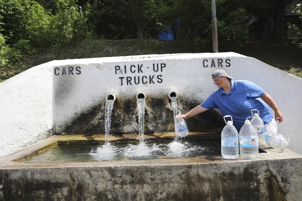 Tarah Nogrady collects water from a trough in Athens, Ohio, on Sunday, July 26, 2020. People have been using it for at least a century, since horses were watered and coal miners would stop by to wipe off grime and dust. They still come - some they think the water is healthier, or makes better coffee, or because their utilities were turned off when they couldn't pay the bills. (AP Photo/Wong Maye-E)