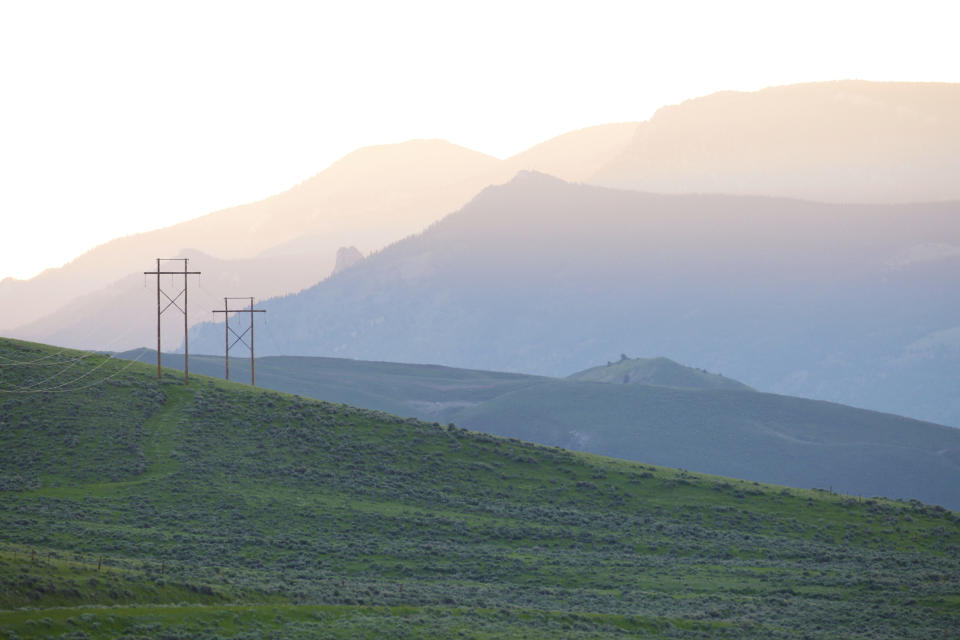 Power lines stand near hills outside Cody, Wyoming on Wednesday, June 15, 2022. The region is ground zero in the conflict between golden eagles and wind energy, which both find homes in areas where there are strong winds. As wind turbines proliferate, scientists say deaths from collisions could drive down golden eagle numbers considered stable at best and likely to drop in some areas. (AP Photo/Emma H. Tobin)