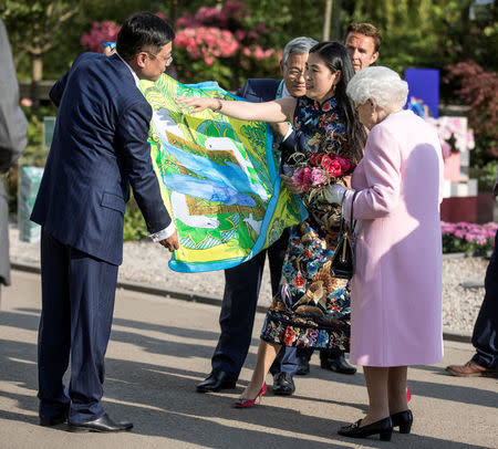 Britain's Queen Elizabeth is presented with a Chinese silk scarf depicting two whales after she looked at the Chinese show garden as she tours the Chelsea flower show in London, Britain May 21, 2018. Richard Pohle/Pool via REUTERS