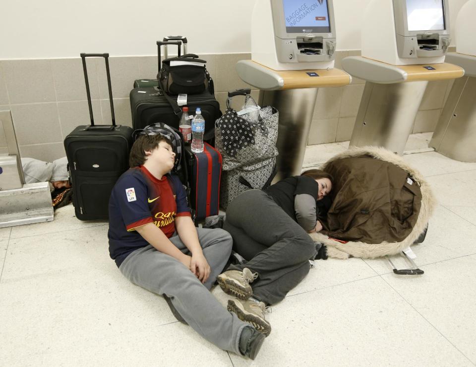 Evan, Ace, and Laura Peagels sleep on the floor in the baggage area of Delta Airlines Terminal 2 at Kennedy International Airport after a Delta flight from Toronto to New York skidded off the runway during icy conditions delaying all air traffic into and out of the airport, Sunday, Jan. 5, 2014, in New York. The family was vacationing in Mexico for a month and are trying to get the kids back to school. Peagel's father is driving four hours from New Jersey to pick them up and deliver them home. (AP Photo/Kathy Willens)