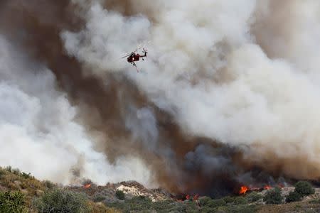 A firefighting helicopter passes over the so-called Sand Fire in the Angeles National Forest near Los Angeles, California, U.S. July 24, 2016. REUTERS/Jonathan Alcorn