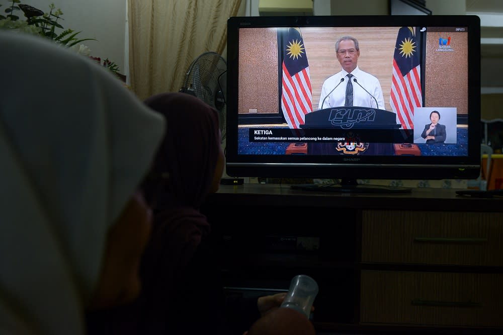 People watching the live telecast of Prime Minister Tan Sri Muhyiddin Yassin’s announcement of a movement control order due to the Covid-19 pandemic in Kuala Lumpur March 16, 2020. — Picture by Miera Zulyana