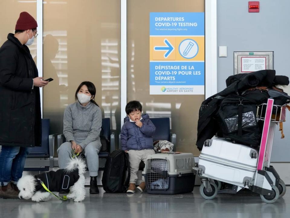 A family waits to travel to the U.S. at Pearson International Airport during the COVID-19 pandemic in Toronto on Friday. New travel testing and restrictions have been put in place due to the newly discovered B.1.1.529 coronavirus variant, now known as omicron. (Nathan Denette/The Canadian Press - image credit)