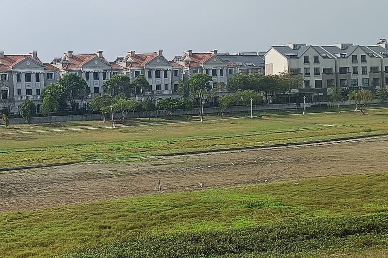 台南市善化區蓮潭公園滯洪池今年2月乾涸，露出一片草原，位於池岸第一排民宅暫時無優美水景相伴。中央社記者楊思瑞攝 112年3月11日