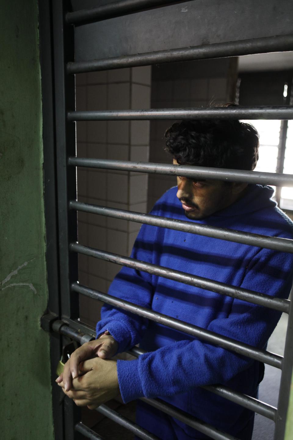 In this May 29, 2013 photo, an inmate looks through a locked door made of bars at the Neuro-Psychiatric Hospital in Asuncion Paraguay. Under funding plagues the hospital. It recently hit a crisis when the hospital couldn't even buy food and there were no psychiatric drugs for ambulatory patients, only inpatients, hospital director Teofilo Villalba. (AP Photo/Jorge Saenz)