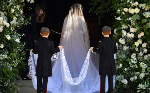 US actress Meghan Markle arrives for her wedding ceremony. Page boys Brian and John Mulroney are pictured holding her train - Credit: AFP