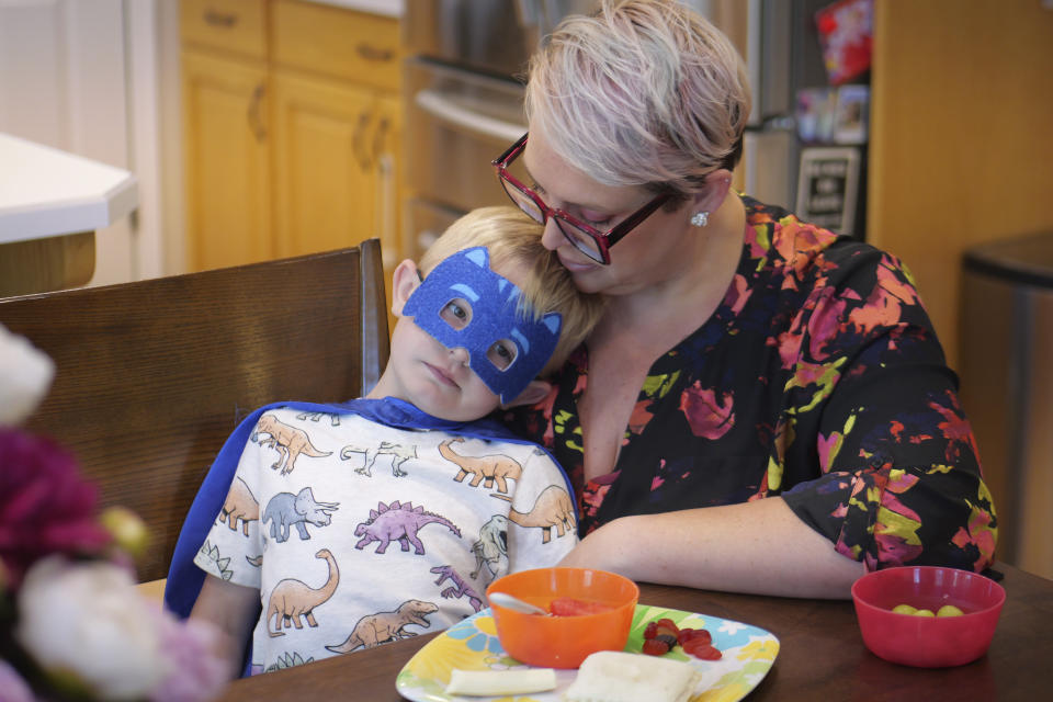 Miles, the little brother of Tyler Thompson, sits with his mother Miranda Thompson during an interview Thursday, May 30, 2024, in West Jordan, Utah. A Utah family whose son was implicated in a thwarted coup in Congo said they're unsure if he is still alive as U.S. officials struggle to make contact with him and two other Americans two weeks after their arrest. Tyler's parents and stepparents passed around a tissue box at the Thompsons' home in West Jordan, Utah, as his brother, Miles, ran around the living room in a superhero costume. (AP Photo/Rick Bowmer)