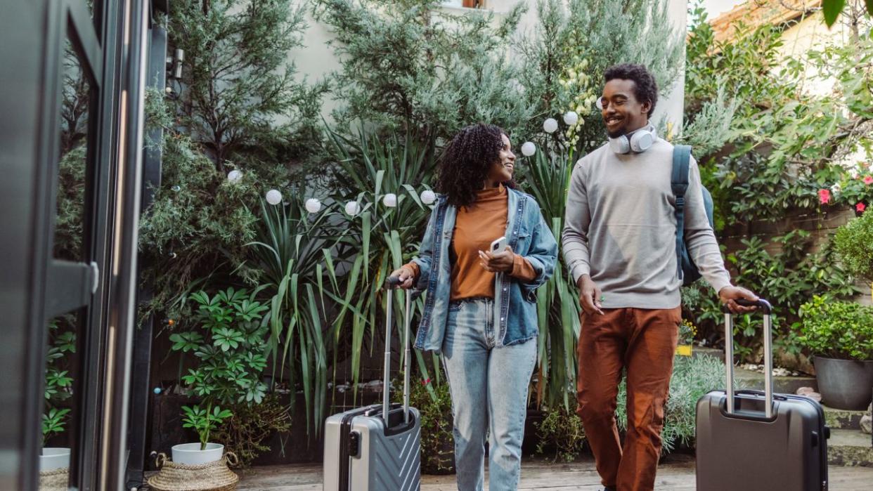 couple walking toward property door with suitcases