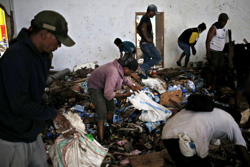 Men scavenge for food inside an abandoned warehouse in an earthquake and tsunami-affected area in Palu, Central Sulawesi, Indonesia Indonesia, Wednesday, Oct. 3, 2018. Clambering over the reeking pile of sodden food or staking out a patch of territory, people who had come from devastated neighborhoods and elsewhere in the remote Indonesian city pulled out small cartons of milk, soft drinks, rice, candy and painkillers from the pile as they scavenge for anything edible in the warehouse that tsunami waves had pounded. (AP Photo/Dita Alangkara)