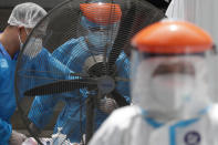 Health workers perform a rapid test on a patient at a parking lot that has been converted into an extension of the Gat Andres Bonifacio Memorial Medical Center in Manila, Philippines on Monday, Aug. 3, 2020. Philippine President Rodrigo Duterte is reimposing a moderate lockdown in the capital and outlying provinces after medical groups appealed for the move as coronavirus infections surge alarmingly. (AP Photo/Aaron Favila)