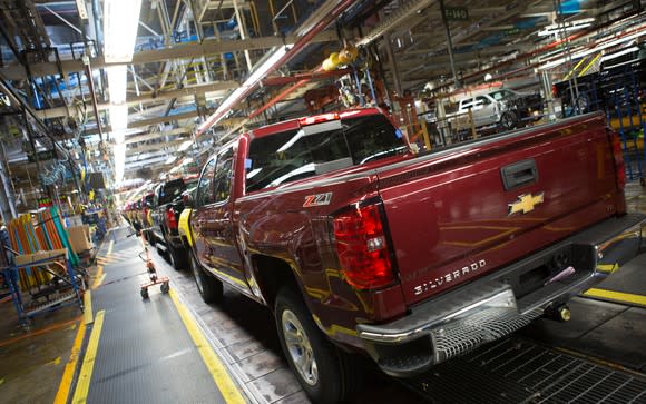 Nearly-complete Chevrolet Silverado pickup trucks are shown on a factory assembly line.