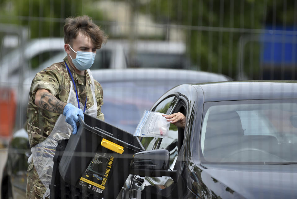 A member of the army collects a test at a coronavirus testing station set up in Victoria Park in Leicester, England, Tuesday June 30, 2020. The British government has reimposed lockdown restrictions in the English city of Leicester after a spike in coronavirus infections, including the closure of shops that don't sell essential goods and schools. (AP Photo/Rui Vieira)