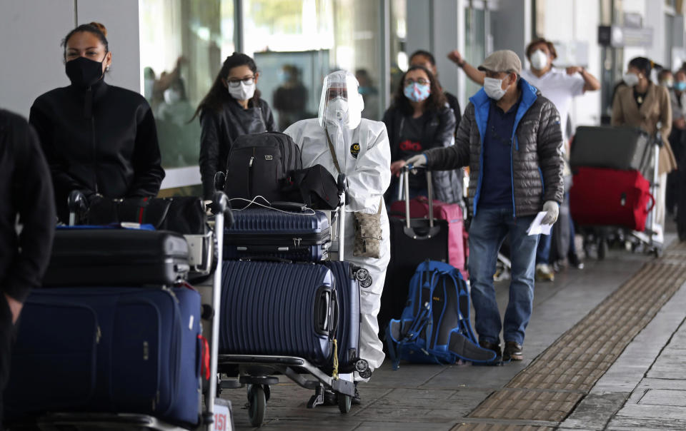 Pasajeros hacen fila para un vuelo humanitario a Italia el lunes 18 de mayo de 2020 usando mascarillas para protegerse del coronavirus, una pandemia que ha ocasionado la cancelación de vuelos nacionales e internacionales en el aeropuerto El Dorado en Bogotá, Colombia. (AP Foto/Fernando Vergara)