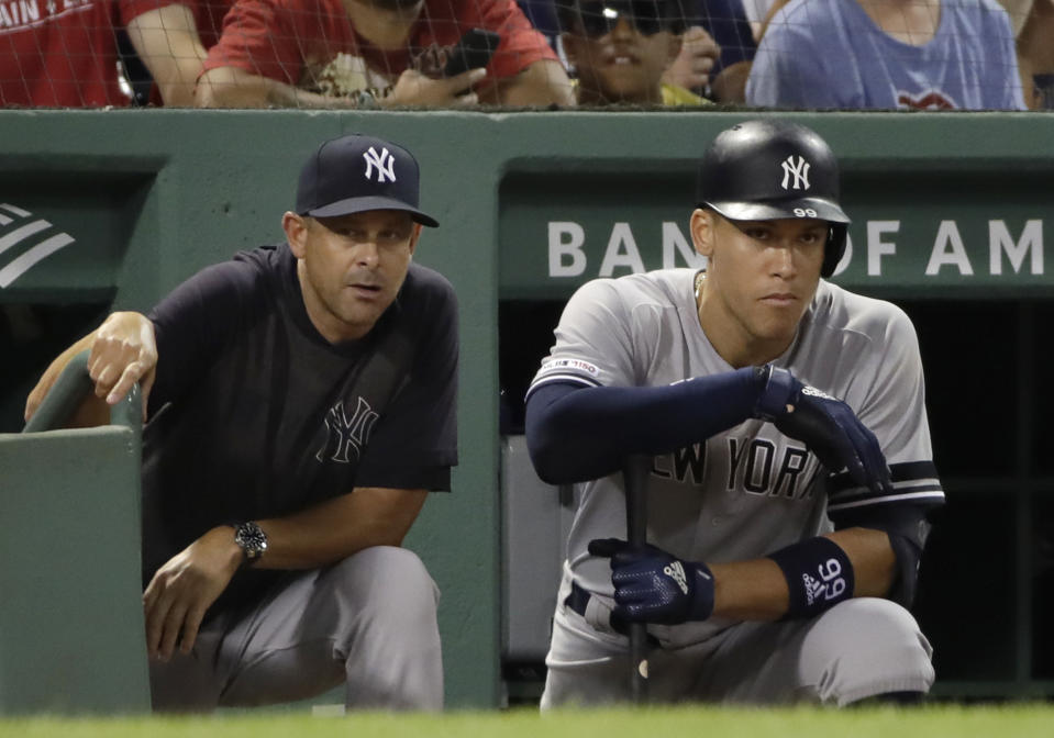 New York Yankees manager Aaron Boone, left, and right fielder Aaron Judge watch from the dugout in the ninth inning of a baseball game against the Boston Red Sox at Fenway Park, Friday, July 26, 2019, in Boston. (AP Photo/Elise Amendola)