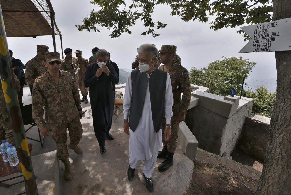 Pakistan's Foreign Minister Shah Mahmood Qureshi, center, Defense Minister Pervez Khattak, 2nd right, walk with a senior army officer during their visit to forward area post along a highly militarized frontier in the disputed region of Kashmir, in Chiri Kot sector, Pakistan, Monday, Aug. 3, 2020. The region's top Pakistani military commander briefed ministers about Indian cease-fire violations in Kashmir, which is split between Pakistan and India and claimed by both in its entirety. (AP Photo/Anjum Naveed)