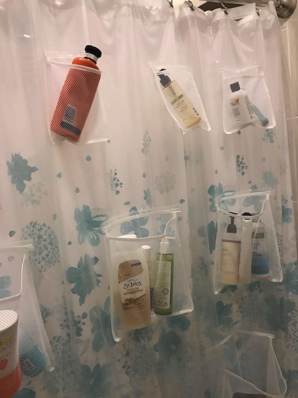 reviewer photo showing the shower curtain with bath products in the pockets 