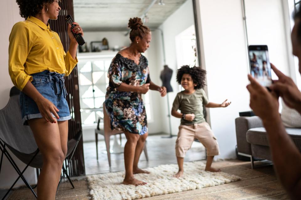 Father filming on smartphone family dancing at home