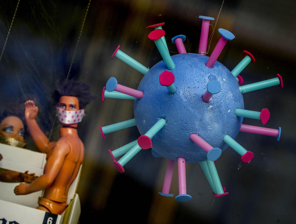 An oversize makeshift Coronavirus and plastic dolls decorated the window of a hairdresser in Frankfurt, Germany, Monday, Sept. 13, 2021. (AP Photo/Michael Probst)