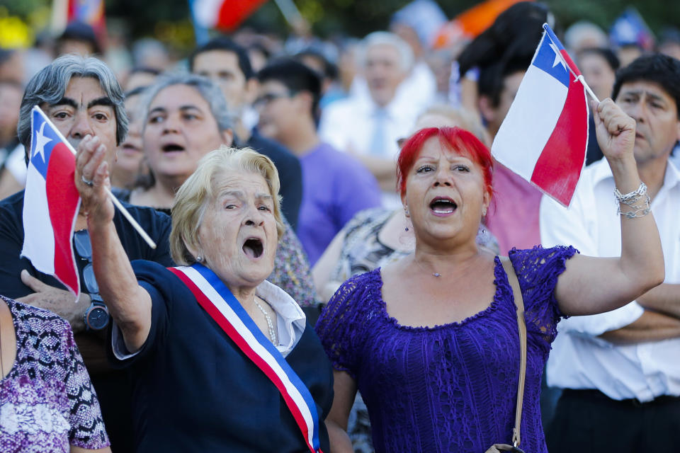 Supporters of President Michelle Bachelet sing the Chilean national anthem and wave Chilean flags outside the La Moneda presidential palace after President Bachelet gave a speech from a balcony in Santiago, Chile, Tuesday, March 11, 2014. Bachelet, who led Chile from 2006-2010, was sworn-in as president on Tuesday. (AP Photo/Victor R. Caivano)