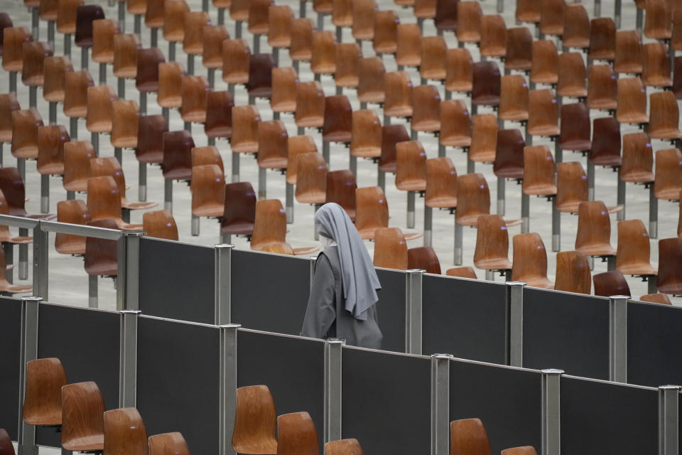 A nun walks past empty seats of the Paul VI hall during the opening of a 3-day Symposium on Vocations at the Vatican, Thursday, Feb. 17, 2022. (AP Photo/Gregorio Borgia)